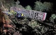 Rescatistas en uniformes amarillos trabajando alrededor de un autobús volcado en un área boscosa, luces de rescate iluminando la escena.