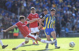 El lateral izquierdo paraguayo de Rosario Central, Agustín Sández, intenta jugar el esférico ante la marca del colombiano Santiago Arias.