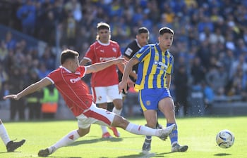 El lateral izquierdo paraguayo de Rosario Central, Agustín Sández, intenta jugar el esférico ante la marca del colombiano Santiago Arias.