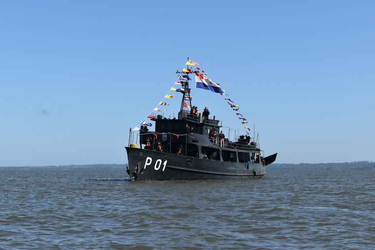 Barco Cañonero Paraguay decorado con banderas, con personas en cubierta. Cielo despejado y ambiente festivo en Encarnación.