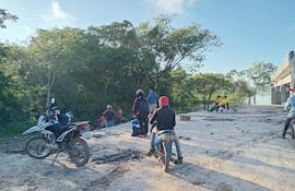Grupo de personas con cascos rojos en un terreno rural, algunas sentadas y otras de pie, alrededor de un área de trabajo inicial.