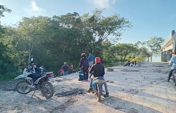 Grupo de personas con cascos rojos en un terreno rural, algunas sentadas y otras de pie, alrededor de un área de trabajo inicial.