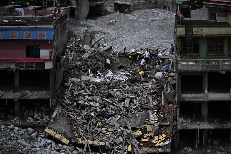 Personas recuperan materiales aprovechables de sus viviendas anegadas por el lodo tras unas inundaciones repentinas en Trishuli Center, en el distrito nepalí de Nuwakot