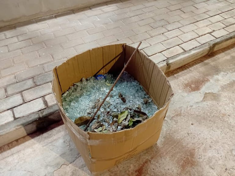 Restos de vidrio templado esparcidos en el pavimento de un local comercial asaltado, sin personas presentes.