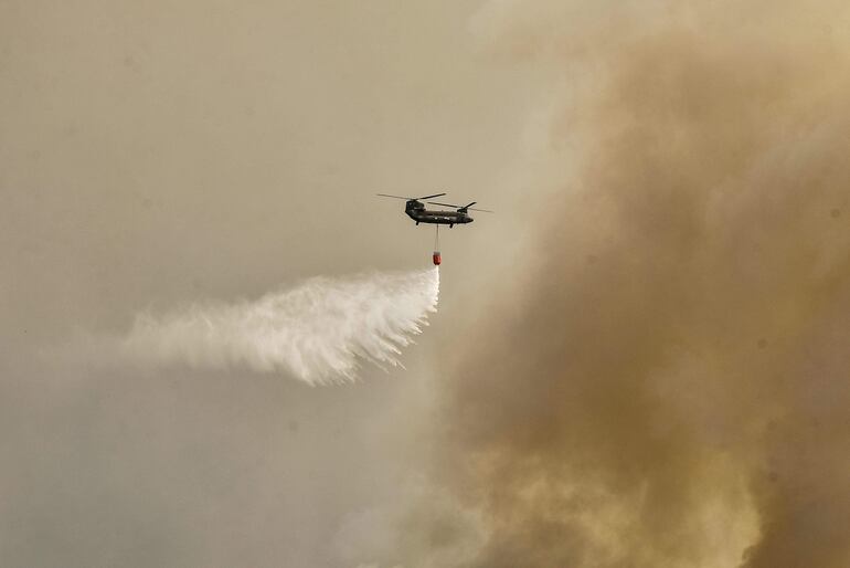 Un helicóptero arroja agua sobre un incendio forestal cerca de Atenas, Grecia, este martes.