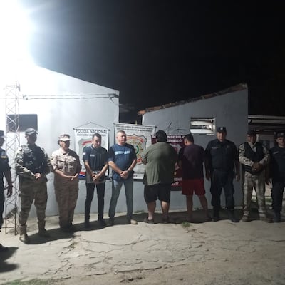 Los dos detenidos de espalada aparecen junto a los agentes de la Policía Nacional que realizan la investigación sobre el hurto ocurrido en Pilar.