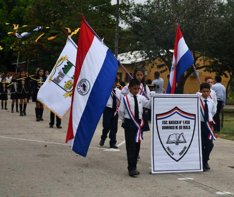 Niños uniformados de la Escuela Básica N° 1456, portando banderas paraguayas