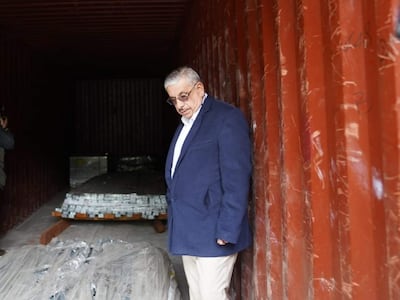 Isaías Fretes con chaqueta oscura y camisa blanca, observa el interior de un contenedor, rodeado de fotógrafos en un ambiente de inspección.