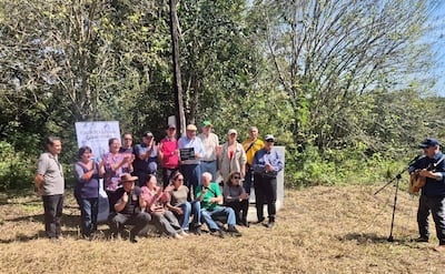 Mujeres y hombres aplauden mientras un hombre toca la guitarra, celebrando en un ambiente rural soleado.