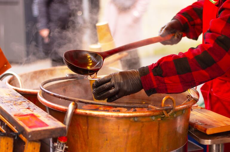 Un hombre sirve glühwein de una cacerola de cobre.