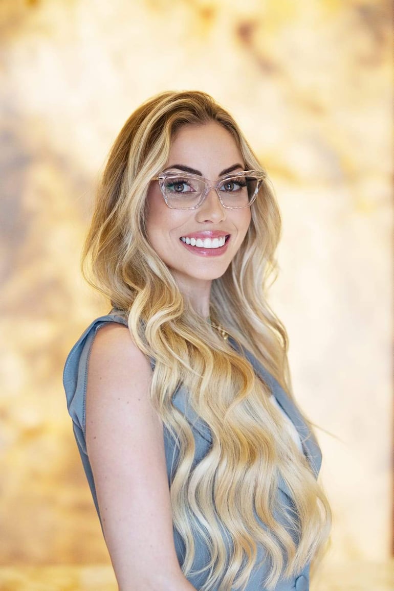 Thalía Kehl sonriente, con cabello rubio y atuendo elegante, mientras comparte su experiencia en un evento sobre lipedema.