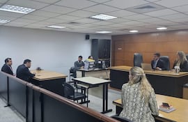 Víctor Nilo Rodríguez en traje oscuro y corbata, sentado junto a otros en un ambiente formal de tribunal.
