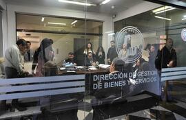 Grupo diverso de personas en oficina, revisando documentos con expresión tranquila y preocupada, en un ambiente de trabajo.