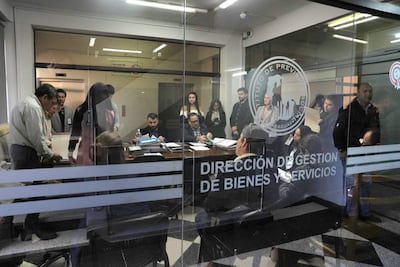 Grupo diverso de personas en oficina, revisando documentos con expresión tranquila y preocupada, en un ambiente de trabajo.