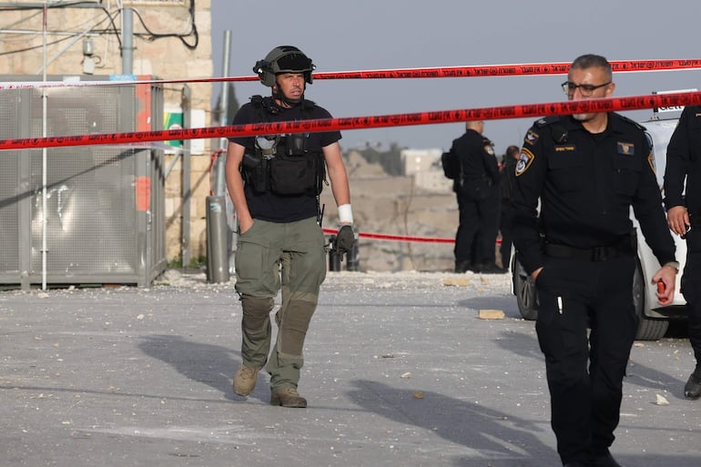 Miembros de la seguridad israelí bloquean un área cercana al barrio judío en Jerusalen donde cayó fragmento de un misil iraní.