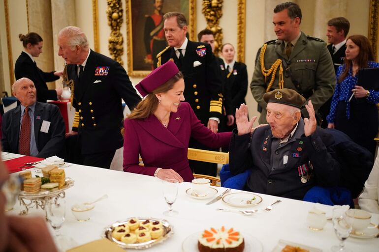 La princesa de Gales habla con un veterano de la Segunda Guerra Mundial, mientras el rey Carlos III de Gran Bretaña llega para sentarse a la mesa durante una fiesta de té en el Palacio de Buckingham para celebrar el 80 aniversario del Día de la Victoria en Europa. (Yui Mok / POOL / AFP)