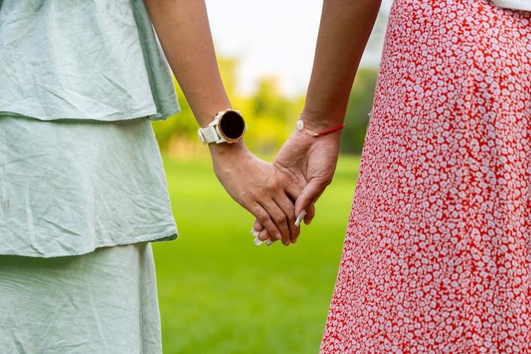 Dos mujeres están tomadas de la mano.
