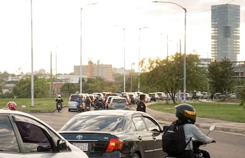 Vista de tráfico en la costanera, con vehículos y motocicletas en fila en un día soleado.