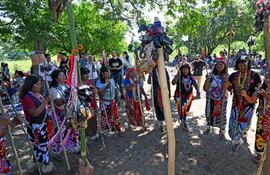 Mujeres del pueblo Maka con trajes tradicionales y varas adornadas, compartiendo alegría en un ambiente natural durante la celebración.