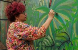 La artista y docente Mavi Servin pintando un mural.