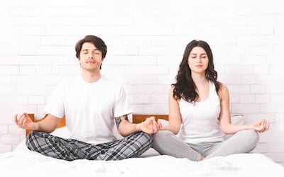 Pareja practicando meditación y respiración consciente.