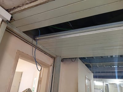 Pasillo del Hospital Nacional de Itauguá con techo deteriorado y cables eléctricos visibles, sin personas presentes.