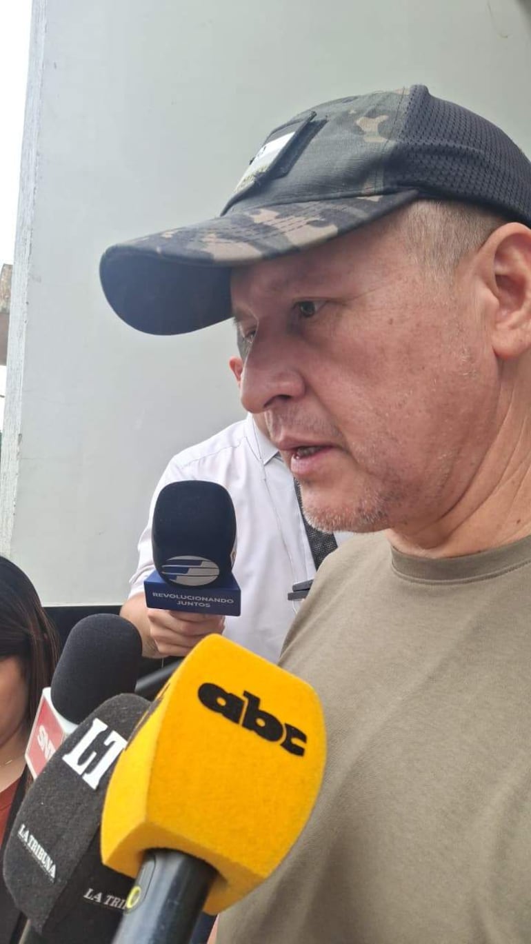 Luis López, con gorra camuflada y camiseta clara, habla ante micrófonos de medios con expresión seria en un ambiente exterior.