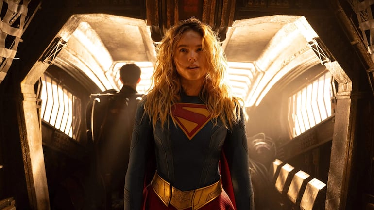Milly Alcock en disfraz de Supergirl, posando con actitud heroica en un fondo sencillo.