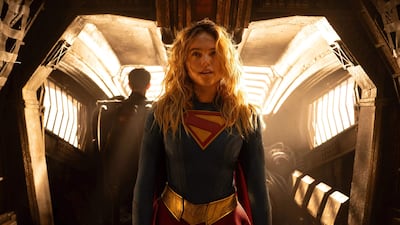 Milly Alcock en disfraz de Supergirl, posando con actitud heroica en un fondo sencillo.