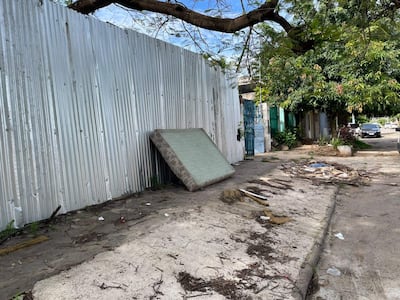 Entorno urbano en Itay con colchón y escombros en la calle, sin personas visibles.