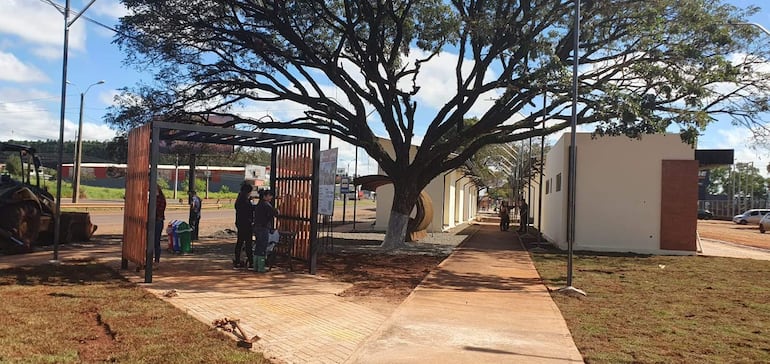 Seis personas en obra pública en Minga Guazú, dos de pie junto a un marco de acceso y otras observando el avance de la construcción.