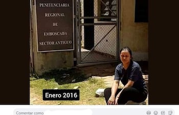 Mujer sentada con camiseta oscura, mirando un letrero de penitenciaría, en un ambiente reflexivo y nostálgico.