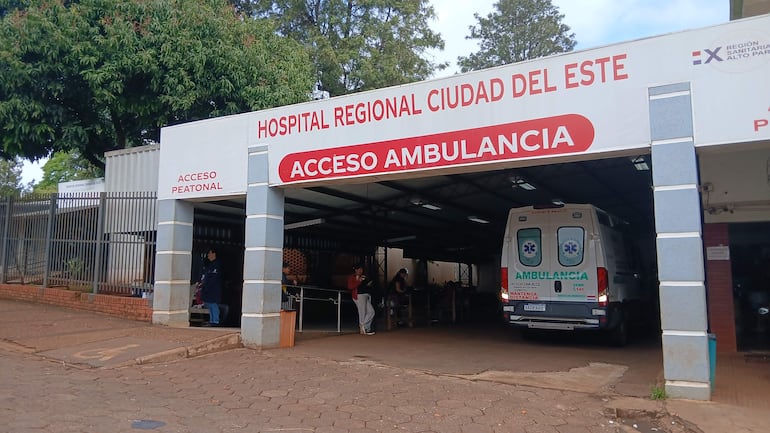 Entrada del Hospital Regional Ciudad del Este con un vehículo de emergencia bajo un toldo de acceso, ambiente tranquilo.