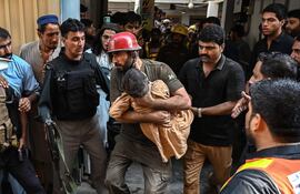 Un rescatista carga a un niño durante una operación de búsqueda tras el derrumbe de un techo en una escuela de Peshawar el 15 de octubre de 2026. (Photo by Abdul MAJEED / AFP)