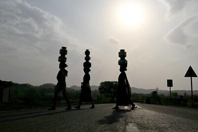 Tres mujeres llevan recipientes con agua en el distrito de Shahaput, en el estado de Maharashtra, India.