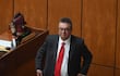 Gustavo Leite, con traje oscuro y corbata roja, se prepara para participar en una discusión en un recinto legislativo.