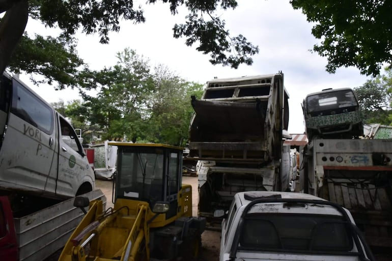 Depósito de vehículos abandonados, camiones y maquinaria pesada deteriorados en un espacio reducido.