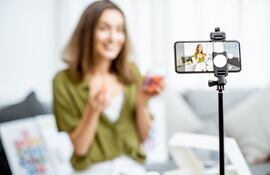 Una mujer graba un vlog con su teléfono celular montado en un trípode.