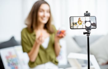 Una mujer graba un vlog con su teléfono celular montado en un trípode.