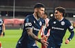 Dos futbolistas con camisetas azules y detalles blancos celebran en el campo, uno apunta al público con gesto entusiasta.
