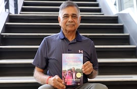 Dr. Prabodh Malhotra sentado en una escalera, mostrando su libro.