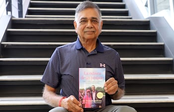 Dr. Prabodh Malhotra sentado en una escalera, mostrando su libro.