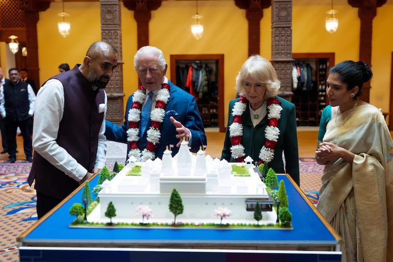 El rey Carlos III y la reina Camila observan una maqueta de un nuevo templo que se construirá en París, durante su visita al BAPS Shri Swaminarayan Mandir, más conocido como el Templo de Neasden, en Londres. (Aaron Chown / POOL / AFP)