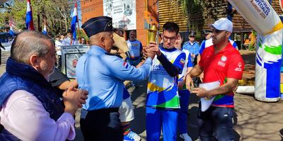 Largada de la carrera de postas de la Llama de la Esperanza, frente a la Municipalidad de Encarnación. El atleta Pedro Brizuela, de Carmen del Paraná, recibe la pira olímpica del director de la Policía Nacional en Itapúa, Com. Gral. Insp. Juan Agüero.