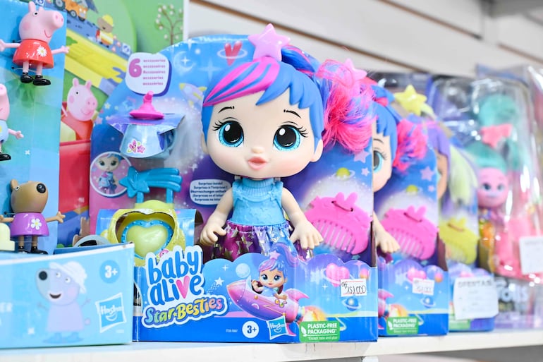 Muñeca Baby Alive Star-Besties en exhibición, con cabello azul y rosa, vestida con detalles estrellados en tienda de juguetes.