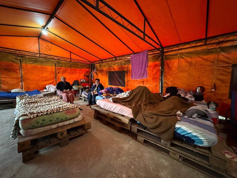 Dos mujeres conversan en un albergue improvisado para familiares de pacientes internados en el Hospital General de San Lorenzo, "Calle´i". Otro familiar, cubierto completamente con una frazada, intenta descansar.