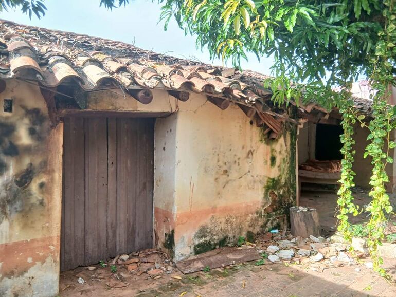 Estructura deteriorada de la Casa de la Cultura, rodeada de vegetación y residuos, sin personas presentes.
