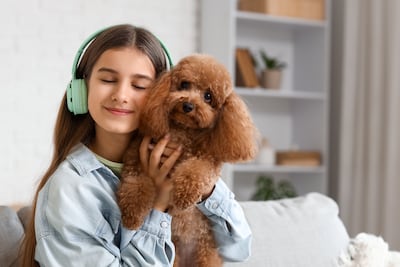 Joven sostiene en brazos a su perro caniche.