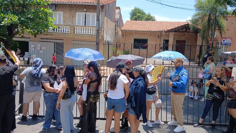 Varias personas utilizan sombrillas para bloquear el sol, aunque estos elementos están prohibidos para el concierto.