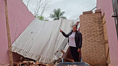 Olga Beatriz Navarro Franco, en camiseta blanca y chaqueta negra, señala chapa caída en cocina-comedor, rodeada de escombros.